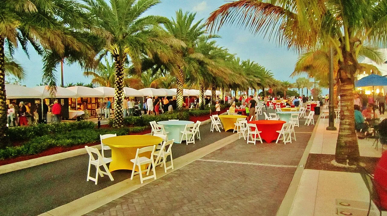 Round tables with yellow and red cloths set under palms on the beachfront promenade