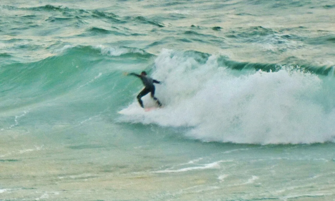 A surfer riding a breaking green wave